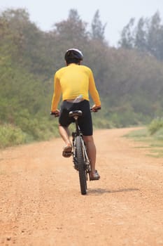 rear view of bicycle man riding on dirt road with drinking water bottle