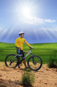 young man standing beside moutain bike ,mtb on hill with sun shining on blue sky use for sport leisure and out door activities extreme sport theme 