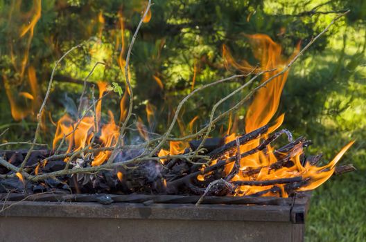 iron grill barbecue with burning charcoal and firewood