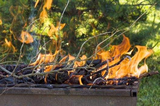 iron grill barbecue with burning charcoal and firewood