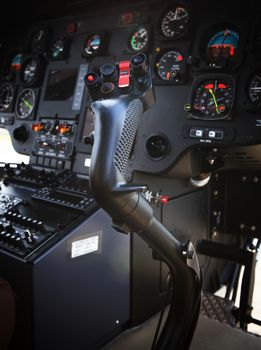 controler joint stick in helicopter cockpit against blackish dashboard guage