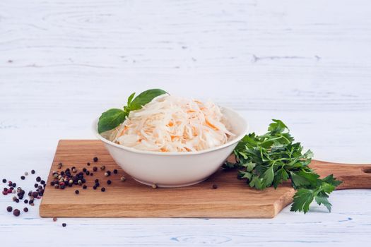 The sauerkraut in bowl, light wooden background