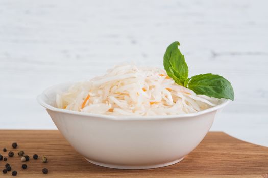 The sauerkraut in bowl, light wooden background