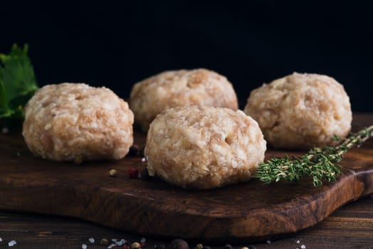 Uncooked meatballs in a dark rustic wooden setting