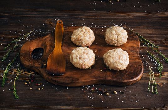 Uncooked meatballs in a dark rustic wooden setting