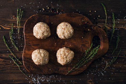 Above view of uncooked meatballs in a dark rustic wooden setting