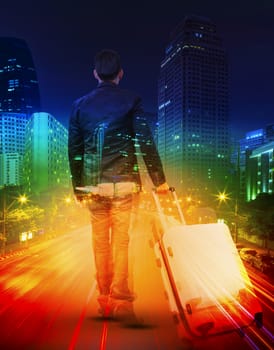 young man with traveling luggage against  lighting of urban scene and colorful of city life