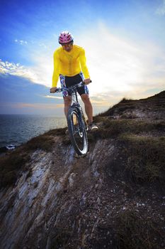 young man riding moutain bike mtb on land dune against dusky sky in evening background use for sport leisure and out door activities theme