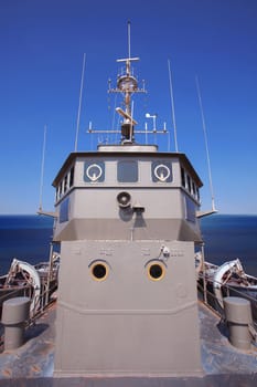 front view of military ship bridge control room against clear blue sea and sky