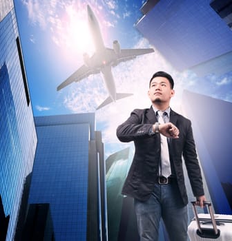business man and belonging  luggage standing against urban building and air plane flying above use for air transportation and people traveling by air liner