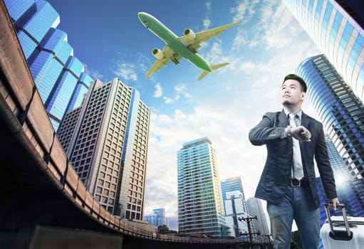 young business man and belonging luggage standing against building urban scene looking to sky with passenger jet plane flying above use for people in traveling theme