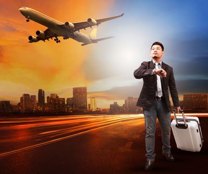 young man and traveling bag luggage standing on city road looking to sky and air plane flying to airport runways use for people traveling theme