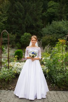 Portrait of a bride in a stylish white dress close-up outdoors