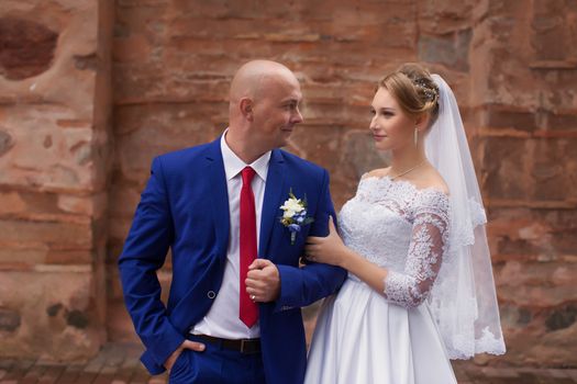 Couple gently embraced on a red brick wall