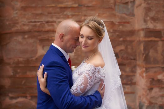 Couple gently embraced on a red brick wall