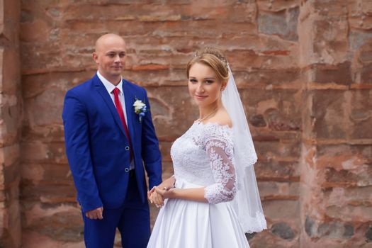 Couple gently embraced on a red brick wall