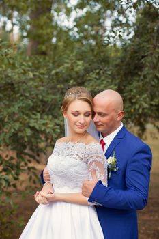 Bride gently pressed her to the groom on the background of nature