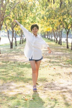 portrait of young beautiful asian woman standing in park with relaxing emotion and smiling face