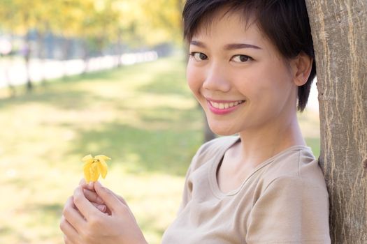 close up face of young asian woman with smiling face and relaxing emotion standing in yellow blooming flowers park use for people healthy life and beauty health care