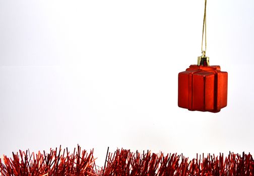 Red christmas gift hanging over a red garland on white background