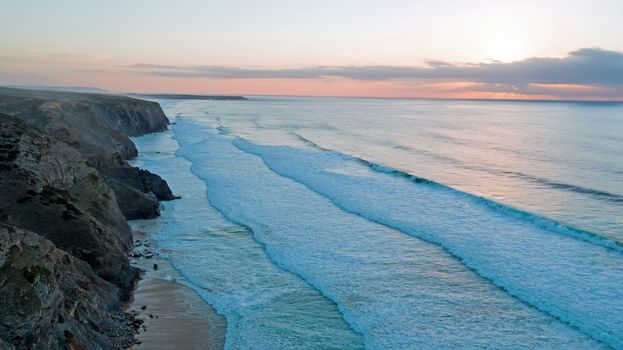 Aerial from rocks and ocean at Praia Vale Figueiras in Portugal at twilight