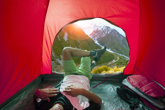 camping man lying in outdoor camping tent with beautiful natural scenic 