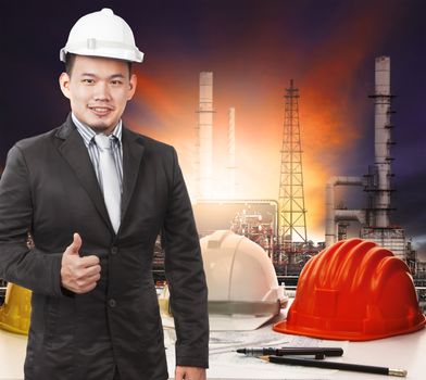 young petrochemical engineer standing in front of working tale of oil refinery industrial and sign good quality control of good manufacturing management company