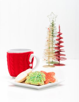 Plate of colorful christmas sugar cookies with a hot beverage.