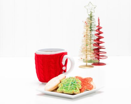 Plate of colorful christmas sugar cookie with a hot drink.