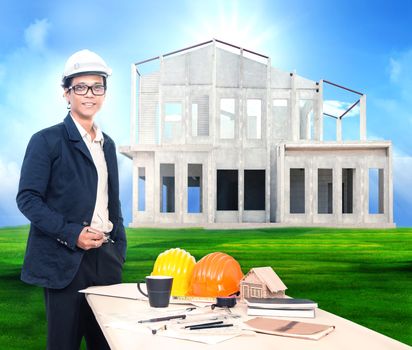 engineering man with working table and home project on beautiful green grass field background use for home ,house construction business