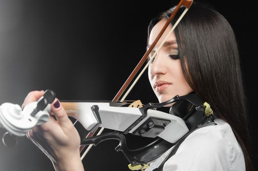 Woman playing the violin on a black background closing her eyes