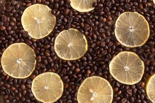 Lemon slices lying among the coffee bean on a wooden table