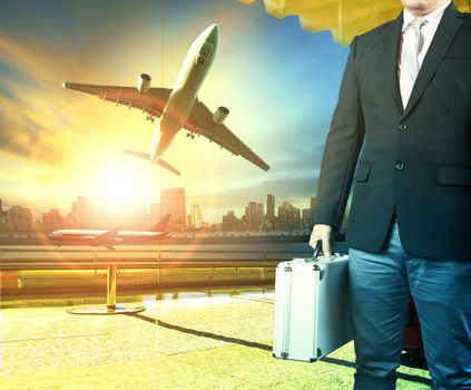 business man and breifcase standing in airport terminal building and passenger plane arrival on runway