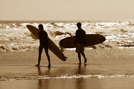 Silhouette of surfers in golden sunset light. Bali