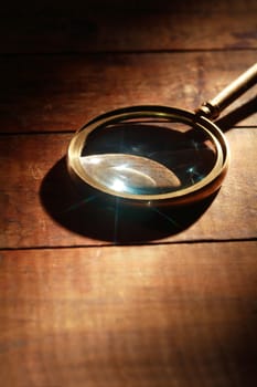 Magnifying glass with long shadow on wooden background