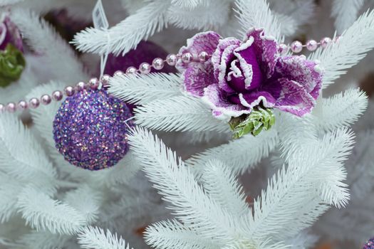 Christmas and New Year seasonal decoration on white fir tree with purple balls and flower ornament