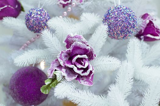 Christmas and New Year seasonal decoration on white fir tree with purple balls and flower ornament