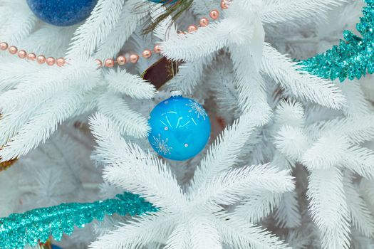 Christmas and New Year seasonal decoration on white fir tree with purple balls and flower ornament
