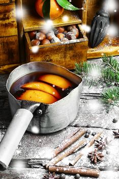 Hot red wine with oranges and cupboard with spices