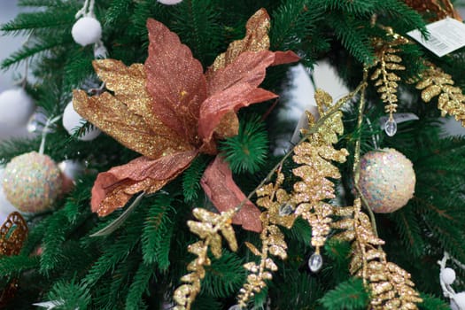 Christmas and New Year seasonal decoration on green fir tree with golden balls and leaves,  orange flower ornament