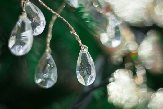Christmas and New Year seasonal background of green tree with bright diamond drops and golden ornaments