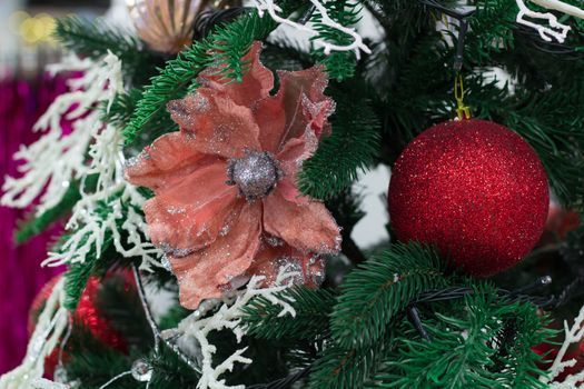 Christmas and New Year seasonal decoration on green fir tree with red balls and flower ornament