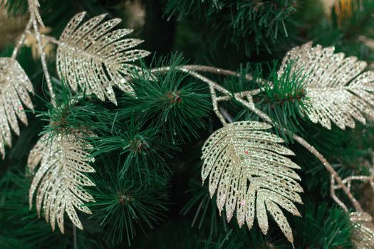 Christmas and New Year seasonal background of green tree branches with bright golden leaves garlands and ornaments