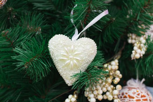 Christmas and New Year seasonal decoration, green tree branches with white heart and golden ornaments