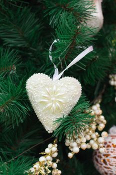 Christmas and New Year seasonal decoration, green tree branches with white heart and golden ornaments