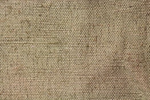 A piece of tarpaulin. The texture of coarse fabric with interwoven threads. Uneven surface. Close-up image for retro backgrounds or texturing.