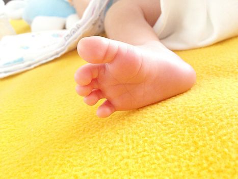 Close-up of a newborn baby's foot on the yellow blanket