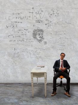 man sitting on desk and physic formula on wall use for knowledge topic and related