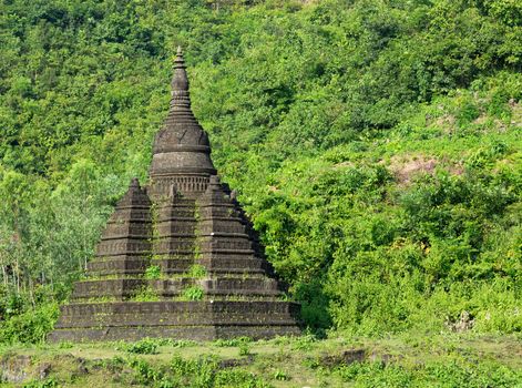Small pagoda in Mrauk U, the Rakhine State of Myanmar, surrounded by lush foliage.