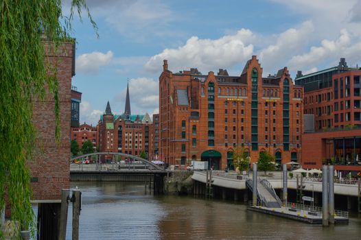 HAMBURG, GERMANY - JULY 18, 2015: a canal of Historic Speicherstadt houses and bridges at evening with amaising skyview over warehouses, famous place on Elbe river.